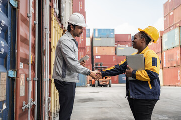 Man hand shake with woman logistics workers in high visibility safety gear discuss operations and checking container at shipping container yard	