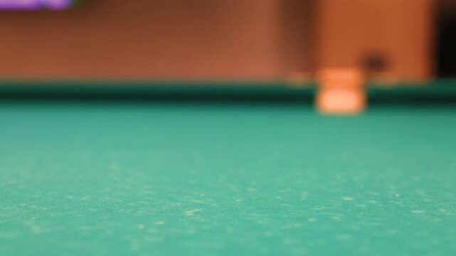 Billiard cue hitting white ball on green felt pool table action shot closeup