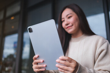 Portrait image of a woman holding and using digital tablet in cafe
