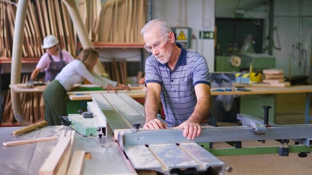 Carpenter cutting wood on a table saw in workshop