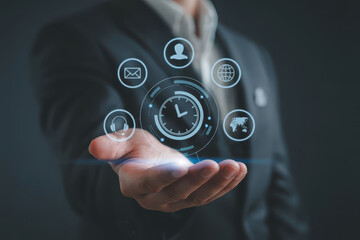 Professional suit holds holographic display featuring various digital icons, symbolizing communication, time management, and global connectivity. This futuristic concept represents modern digital