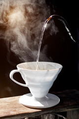 Pouring hot water into a ceramic coffee dripper with visible steam and dramatic sunlight, capturing the cozy, warm atmosphere of a relaxing morning routine.