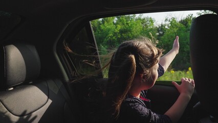 little girl child kid waving hand through car window, child girl feeling breeze hair, traveling by car with windows open, child child enjoying summer breeze, feeling freedom, sunset ride brings joy