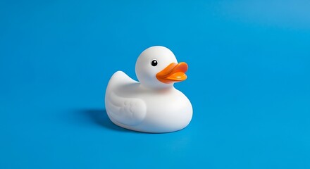 A singular white rubber bird with an orange beak sits centered against a solid, bright, blue background, casting a soft shadow