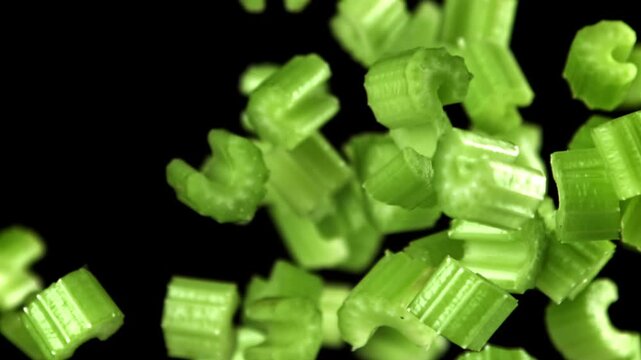 Sliced pieces of celery rise and fall on a black background. Filmed on a high-speed camera at 1000 fps. High quality FullHD footage