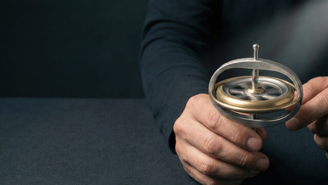 Person holding spinning gyroscope toy symbolizing start up business concept with focus on innovation and balance in dark setting