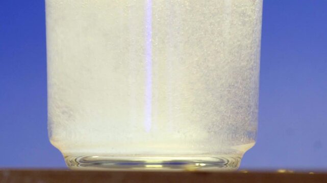Effervescent tablet dissolving in water with a blue background