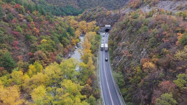 A drone captures a moving vehicle entering a tunnel in nature, with the Struma River flowing beside the road in Bulgaria.