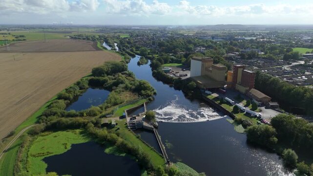 Aerial drone cinematic panorama of Ferrybridge hydroelectric energy plant with huge weir on River Aire and industrial factories along banks Yorkshire UK