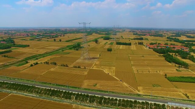 High-Voltage Power Transmission Tower Over Agricultural Farmland Landscape