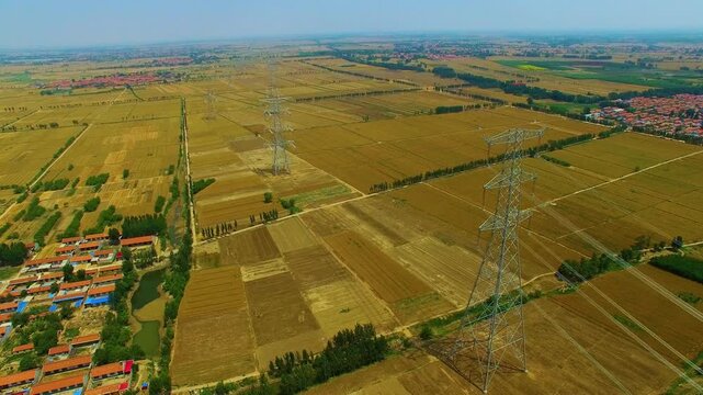 High-Voltage Power Transmission Towers Over Agricultural Fields Aerial View