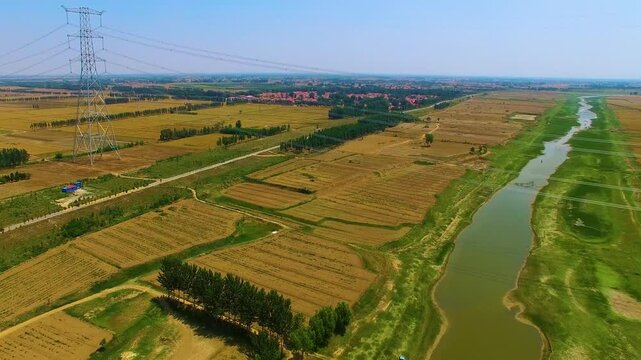 High Voltage Tower Over Agricultural Fields and River - Aerial Landscape