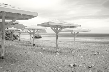 Wooden awnings on a deserted sandy beach overlooking the sea. Color of the Year 2026, Cloud Dancer.