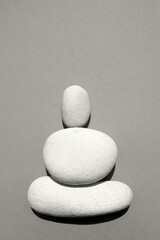 Three white smooth stones on top of each other on a beige background. Color of the Year 2026, Cloud Dancer.