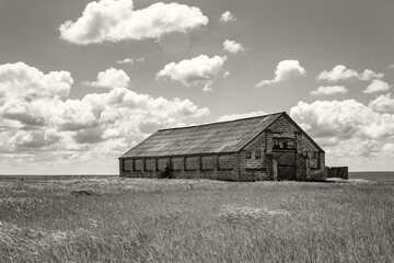 Old abandoned house made of stone on a background of sky and grass. Color of the Year 2026, Cloud Dancer.