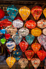 A vibrant display of traditional handmade silk lanterns hanging in the historic old town of Hoi An, Vietnam, during a local market. A symbol of Vietnamese culture, light, and tradition.