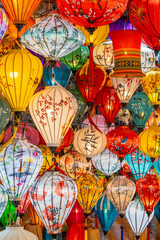 A vibrant display of traditional handmade silk lanterns hanging in the historic old town of Hoi An, Vietnam, during a local market. A symbol of Vietnamese culture, light, and tradition.