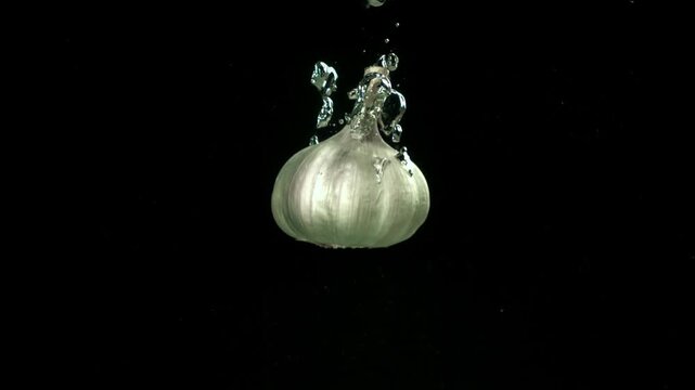 The heads of fresh garlic fall under the water. Filmed on a high-speed camera at 1000 fps. High quality FullHD footage