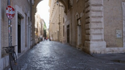 Narrow cobblestone street framed by historic brick buildings and archway, softly defocused street; background backdrop copyspace calm.