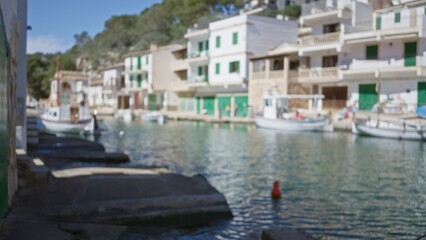 Fototapeta premium Blurred view of cala figuera port in mallorca with boats moored along the waterfront and buildings in the scenic background.