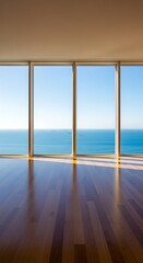 Wide windows offer panoramic ocean views and reflect light on a polished wooden floor.