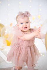 little blue-eyed girl in pink dress celebrates her first birthday