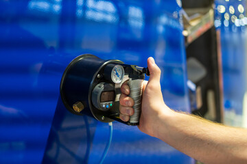 An aviation technician performing an elasticity check on the blue aeroplane rudder surface using a handheld pressure gauge tool during aircraft maintenance and quality control inspection
