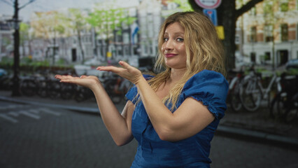 Fototapeta premium Woman presenting open palms on a street with parked bicycles, wearing blue dress and showing hands and shoulders; skepticism curiosity.