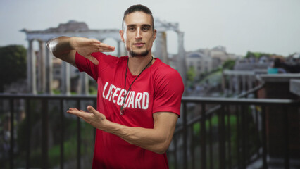 Lifeguard man in red shirt frames empty space with hands, showing forearm and whistle on chest on...