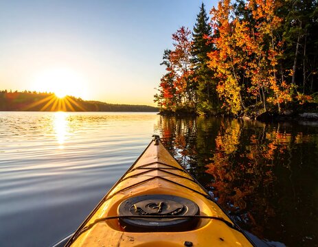Kayak view on serene lake with autumnal trees and sunset