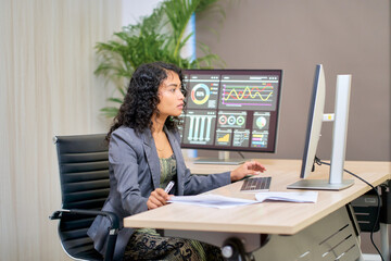Mixed businesswoman in suit working with many monitor for analyzt data and graph for business forecast.
