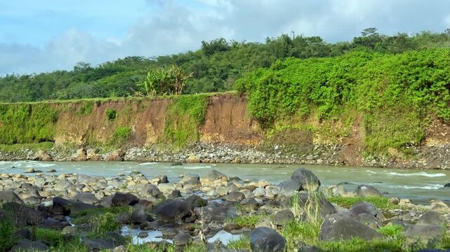 A serene and expansive natural landscape with a wide flowing river with rocky banks. Cinematic Nature video