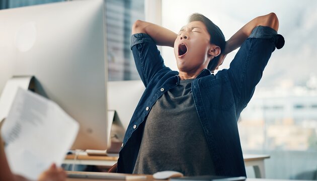Tired asian male project manager yawning with arms behind head in office desk. Concept for office life, business fatigue and corporate exhaustion