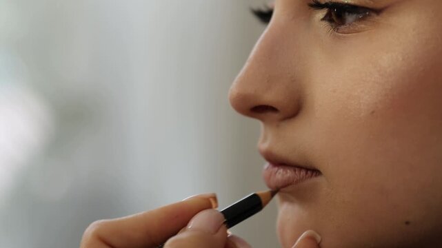A makeup artist gently applies lipstick to a young woman during a beauty session.