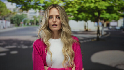 Naklejka premium Woman puts her arms in an angry stance on a street near a young blonde outdoors wearing a cardigan colored pink.