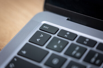 Close-up of the ESC key on a laptop keyboard. Symbol of exit, cancel, return and escape command. Modern technology detail for IT, coding, digital workflow and computer use.