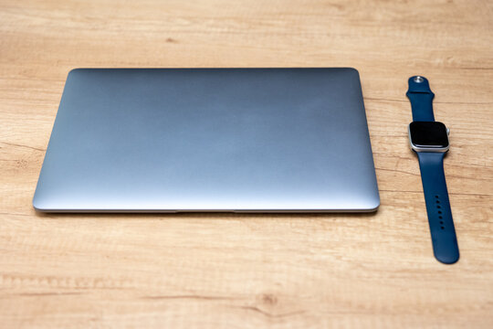 Closed laptop and smartwatch on a wooden desk. A modern workspace symbolizing productivity, technology, and the need to control time spent working at the computer. Suitable for Men’s Day themes.