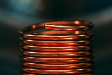 Copper wire coiled into a coil or spiral, closeup with a blurred industrial background