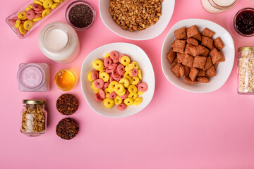 Dry breakfast and milk. Dry sweet breakfast - corn rings, chocolate corn pillows and granola, milk, yogurt and honey on a pink background. Quick and nutritious breakfast