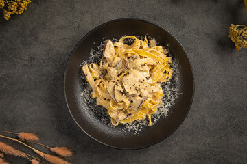 Creamy tagliatelle pasta with mushrooms and cheese served on a dark plate with rustic elegant styling