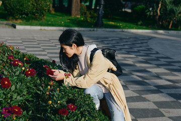 A female gardener kneels beside flowers in a park, selecting petals with focus and care, showcasing gardening, outdoor activity, and nature appreciation in a calm daylight setting