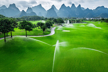 Fototapeta premium Automatic irrigation system watering the green grass on golf course field.