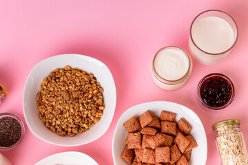 Dry breakfast and milk. Dry sweet breakfast - corn rings, chocolate corn pillows and granola, milk, yogurt and honey on a pink background. Quick and nutritious breakfast