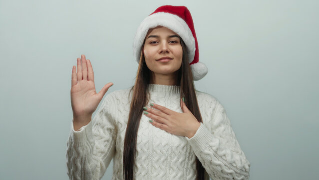 Woman in santa hat and sweater pledging allegiance over white background