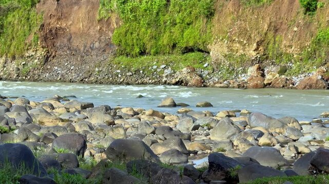 Static Video Natural river view with flowing water, large rocks and green cliff edges in the sunlight. Cinematic Nature video