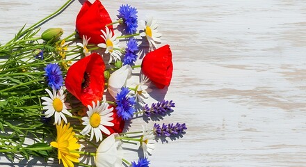 Red poppies, daisies, and blue cornflowers adorn a weathered wooden surface.