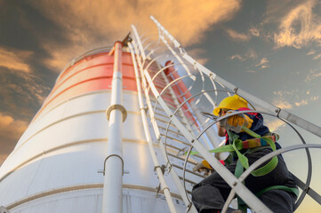 An industrial worker ascending a tall concrete silo with full safety gear, highlighting construction workflow and industrial operations. © เลิศลักษณ์ ทิพชัย