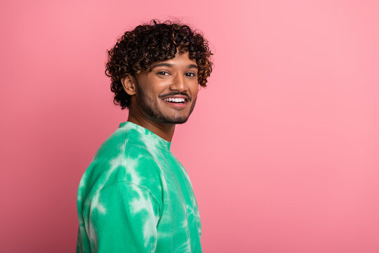 Smiling young man in green tie dye sweater against pink background ready for lifestyle fashion shoot