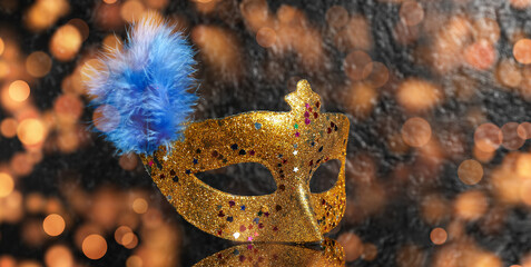 Beautiful golden carnival mask with feather on black background