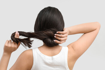 Fototapeta premium Beautiful young woman with healthy long hair on grey background, back view